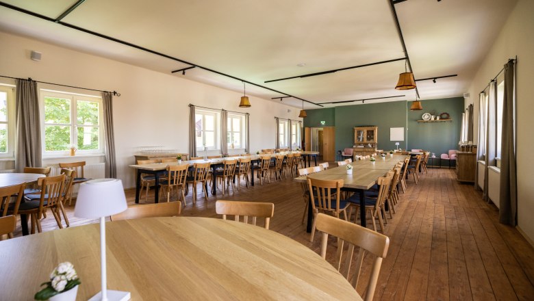 Saal im Obergeschoss des Gasthauses, © Wiener Alpen, Martin Fülöp Ein großer, heller Saal mit Holzböden und Holztischen und -stühlen. Fenster an der linken Wand lassen Tageslicht herein. Der Saal ist modern gestaltet, eine Wand grün gestrichen, der Rest weiß.