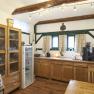 Frühstücksraum, Gästezimmer Victoria, © Marianne Graf Ein gemütlicher Frühstücksraum mit Holzmöbeln, einem Kühlschrank, einer Kaffeemaschine und dekorativen Holzbalken an der Decke.