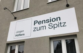 Pension zum Spitz, © Pension zum Spitz Fassade eines Gebäudes mit einem Schild der Pension zum Spitz.