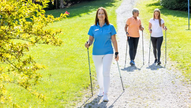 Geführtes Nordic Walking im Gesundheitsresort Königsberg, © Andreas Thiesz Drei Personen beim Nordic Walking auf einem Kiesweg in einem grünen Park. Eine der Personen ist eine Trainerin des Gesundheitsresorts Königsberg.