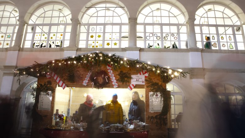Christkindlmarkt im Schloss Katzelsdorf, © Wiener Alpen/Stefanie Reisenbauer Weihnachtlich dekorierter Punschstand mit Lichtern und Menschen davor, im Hintergrund das Schloss Katzelsdorf