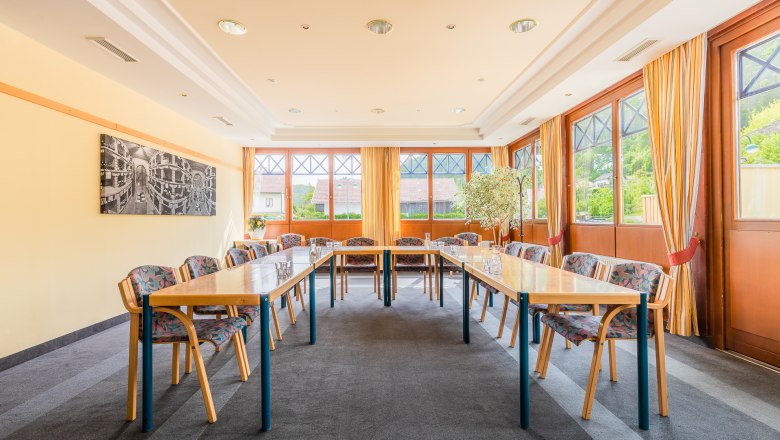 Seminarraum Wintergarten, © Kremsl Ein heller Seminarraum mit Tischen in U-Form, Stühlen und großen Fenstern mit Vorhängen.