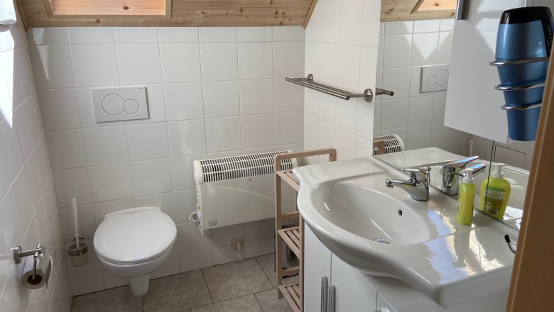 Badezimmer, © Wiener Alpen Modernes Badezimmer mit Dachfenster, Waschbecken, Toilette und Handtuchhalter.