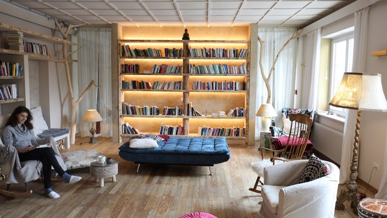 Bibliothek, © Seminarhotel NaturSinne Gemütliche Bibliothek mit großen, beleuchteten Bücherregal, Sesseln und einer Person, die liest.