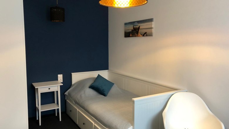 Einzelzimmer, © Pension zum Spitz Ein kleines, modern eingerichtetes Einzelzimmer mit einem Bett, einem Nachttisch und einem Stuhl.