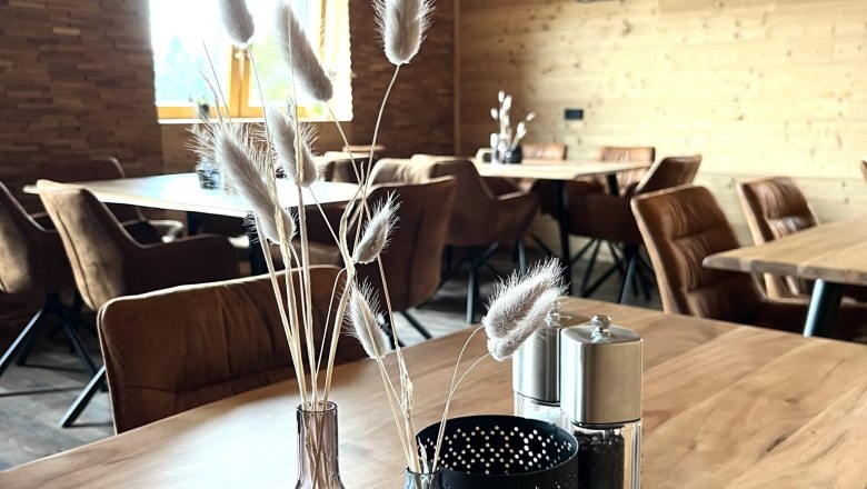 "dahoam" sein in Hollenthon, © Anita Gradwohl, dahoam Gemütlicher Raum aus Holz, Dekoration auf Holztisch, Schriftzug 'dahoam' an der Wand.