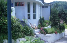 Roomantic Apartments, © Roomantic Apartments Eingang eines modernen Gebäudes mit Garten und Treppe.