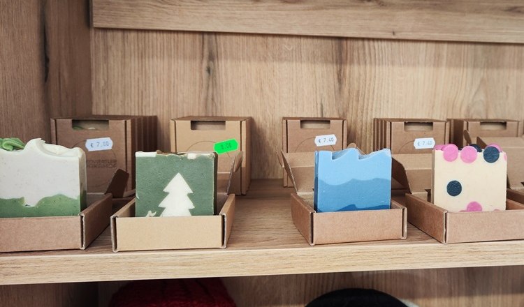 Handgemachte, natürliche Seifen aus Alpkawolle, © Wiener Alpen Handgemachte Seifen in verschiedenen Farben und Mustern auf einem Holzregal.