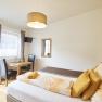 Zimmer Riesling, Gästezimmer Victoria, © Marianne Graf Helles Gästezimmer mit Bett, Tisch, Stühlen und Fernseher.
