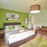 Zimmer Veltliner, Gästezimmer Victoria, © Marianne Graf Modern eingerichtetes Gästezimmer mit grünem Akzent, Doppelbett, braunem Sessel und dekorativem Bild an der Wand.