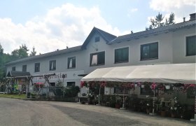 Waldpension Stachl, © Wiener Alpen Ein zweistöckiges Gebäude mit der Aufschrift 'Waldpension', umgeben von Blumen und einem Vordach.