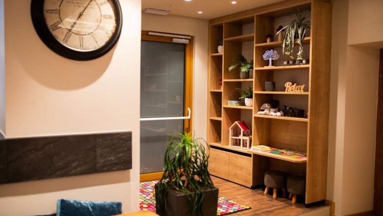 Saal im Koll Bistro Kirchschlag, © Koll GmbH Innenansicht eines Bistros mit großer dekorativer Uhr, Regal und Kinderspielecke.