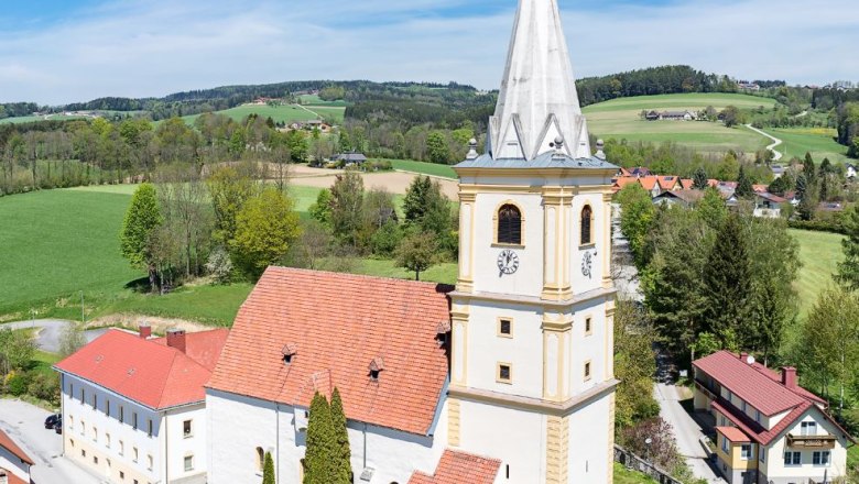 Wehrkirche Krumbach, © Walter Strobl, www.audivision.at Luftaufnahme der Wehrkirche Krumbach in einer ländlichen Umgebung mit grünen Feldern und blauem Himmel.
