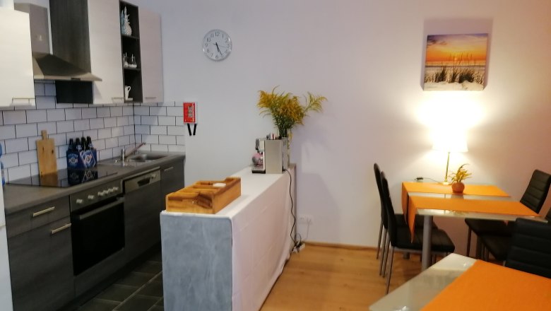 Küche im Frühstücksraum, © Pension zum Spitz Moderne Küche mit Esstisch und orangen Tischsets.