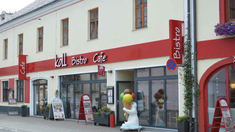 Koll Bistro Kirchschlag, © Koll GmbH Außenansicht des Koll Bistro Cafés mit rotem Schild und Eisbärfigur mit Eis-Stanizel vor dem Eingang.