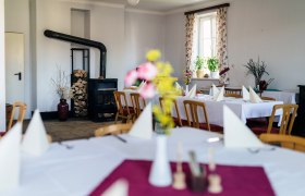 Gasthaus Stocker in Lembach, © Nicole Heiling Ein gemütlicher Gastraum mit Holzofen, gedeckten Tischen und Blumen auf den Tischen.