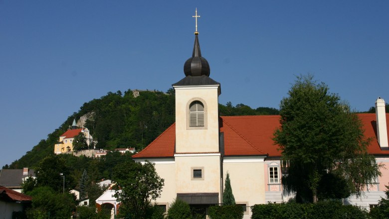 Pfarrhof Pitten, © Thermengemeinden Pfarrhof Pitten mit Kirche und Hügel im Hintergrund.