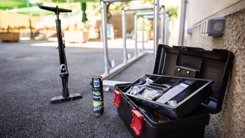 Radpartner s'Hutwisch mit Equipment, © Wiener Alpen, Martin Fülöp Fahrradwerkzeug, Kettenöl und Pumpe neben Fahrradständern im Freien.