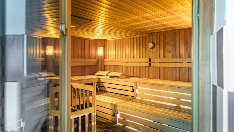 Sauna, © Kremsl Innenansicht einer leeren Sauna mit Holzbänken und Wanduhr.