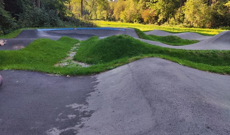 Pumptrack Bad Schönau, © Wiener Alpen Pumptrack mit Asphalt und Gras in einer bewaldeten Umgebung.