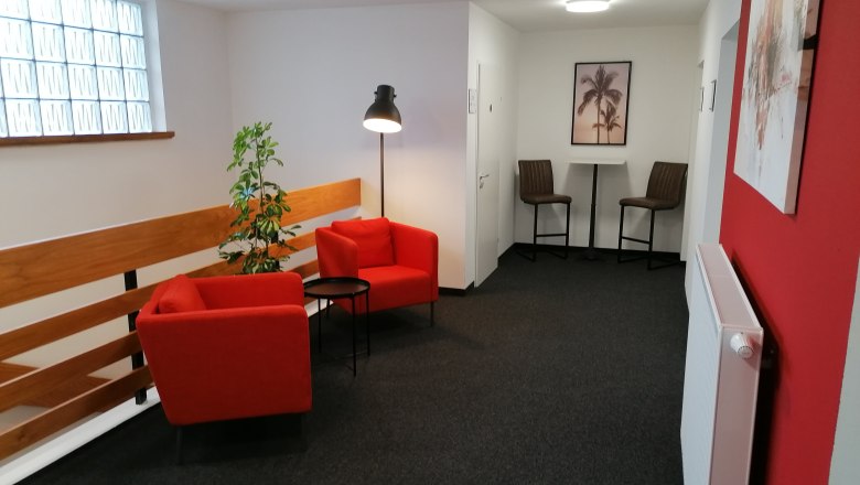 Pension zum Spitz, © Pension zum Spitz Gemütliche Sitzecke mit roten Sesseln und Stehlampe in einem Flur.