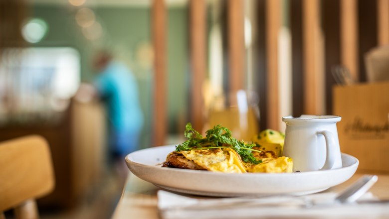 Speisen im s'Hutwisch, © Wiener Alpen, Martin Fülöp Ein Teller mit Omelett und Kräutern auf einem Tisch in einem Restaurant.