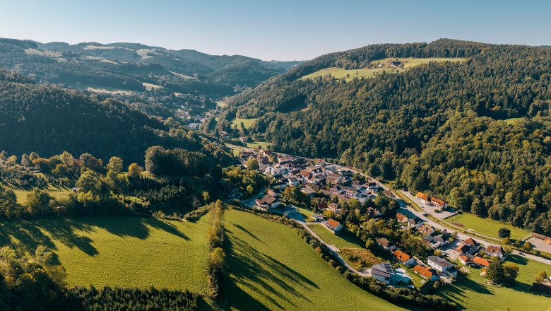 Ortskern Edlitz mit Wehrkirche, © Wiener Alpen/Roman Königshofer Photography Luftaufnahme von Edlitz mit Wehrkirche, umgeben von grünen Hügeln und Wäldern.