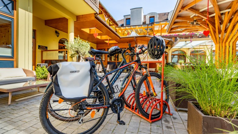 Fahrradparkplatz beim Hotel Post-Hönigwirt, © Wiener Alpen/Martin Fülöp Fahrräder an einem Fahrradständer vor einem Hotelgebäude.