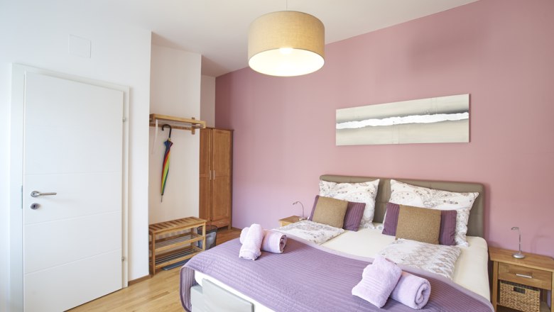 Zimmer Rosé, Gästezimmer Victoria, © Marianne Graf Ein gemütliches Gästezimmer mit rosa Wand, Doppelbett und moderner Einrichtung.