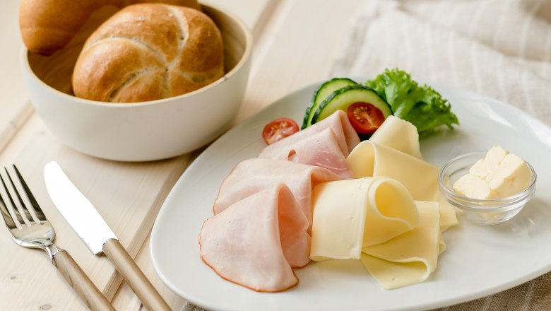 Koll Frühstück, © Koll GmbH Frühstücksteller mit Schinken, Käse, Gurken, Tomaten und Brötchen.