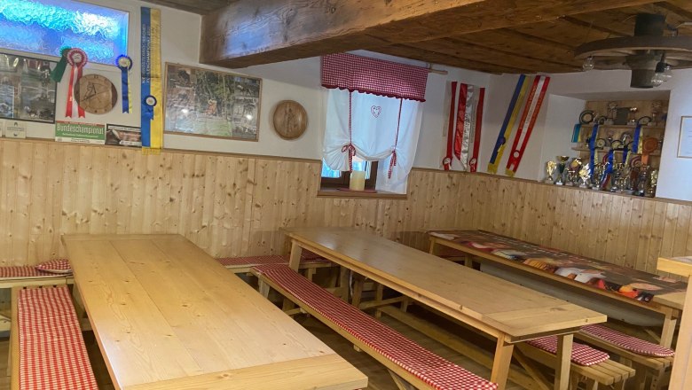 Gemeinschaftsraum Haflingerhof Luef, © Wiener Alpen Gemütlicher Gemeinschaftsraum mit Holztischen, Bänken und Dekorationen an den Wänden.