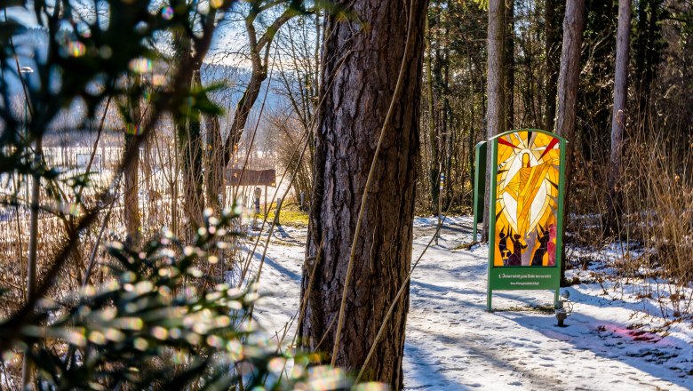 Gläserner Kreuzweg, © Wiener Alpen, Flotoanker - Luckerbauer Winterlicher Waldweg mit Sonne und religiösem Bild aus Glas.