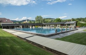 Freibad Krumbach, © SchwimmbadKrumbach©Marktgemeinde Krumbach, Foto: Franz Riegler Freibad Krumbach mit Schwimmbecken und Sprungblöcken, umgeben von grüner Landschaft und Gebäuden.