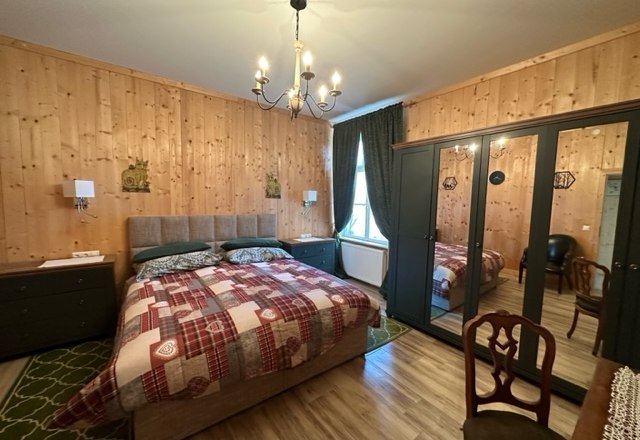 Zimmer Superior, © Schloss Gut Ziegersberg Gemütliches Schlafzimmer mit Holzwänden, Doppelbett, Spiegelkleiderschrank und Kronleuchter.