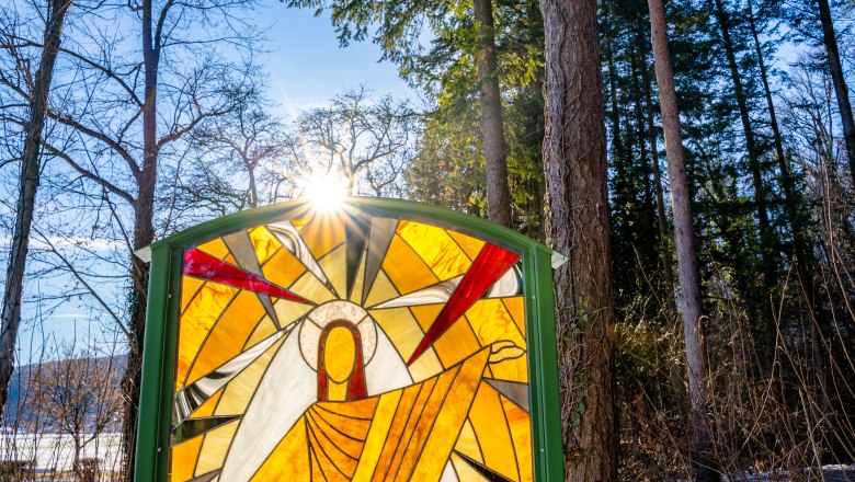 Tiffany-Glastafel am Gläserner Kreuzweg im Winter, © Wiener Alpen, Flotoanker - Luckerbauer Von der Sonne beleuchtetes Buntglasfenster im Wald