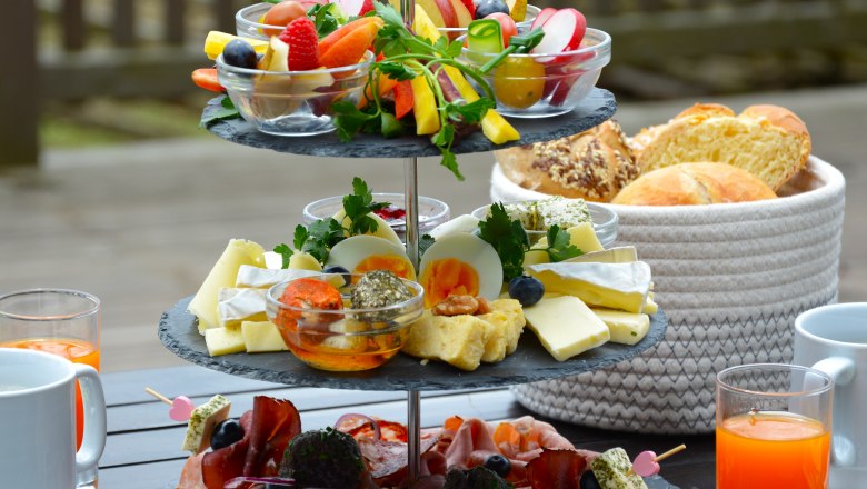 Frühstücksvariationen, © das Turmcafé - Gemeinde Schwarzenbach Etagere mit Aufschnitten, Käse und Gemüse, daneben Getränke und ein Brotkorb.