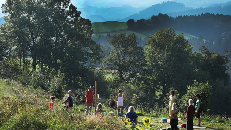 Yoga, © Seminarhotel NaturSinne Gruppe von Menschen macht Yoga im Freien vor einer malerischen Berglandschaft.