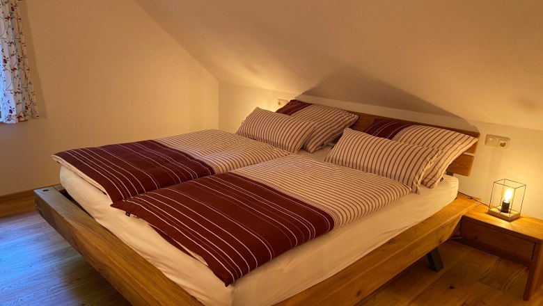 Gemütliches Doppelzimmer mit Holzbett und gestreifter Bettwäsche.