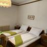 Gemütliches Doppelzimmer mit zwei Einzelbetten, Holzmöbeln und einer dekorativen Lampe.