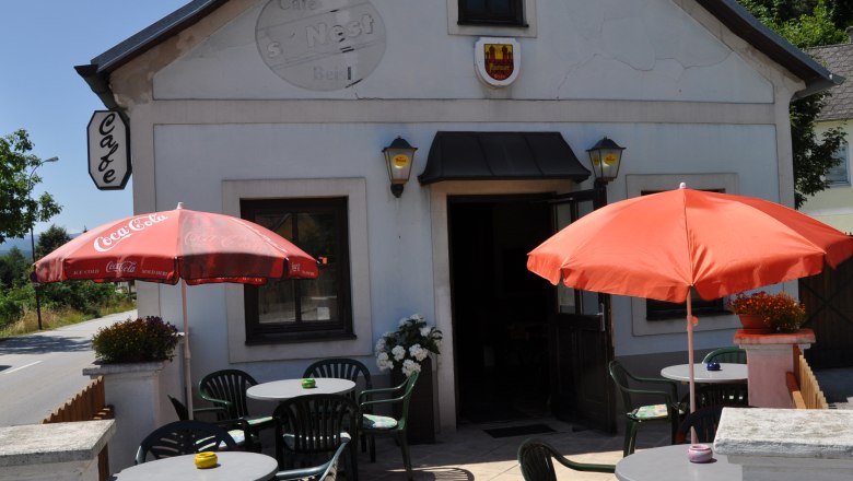 Au&szlig;enansicht eines Caf&eacute;s mit Terrasse, Tischen und Sonnenschirmen.