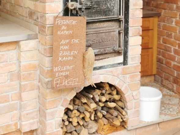 Backofen aus Ziegelsteinen mit Holzlagerung und Dekorationen unter einem Holzdach.