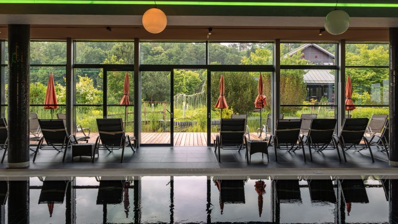 Innenansicht eines Spas mit Liegestühlen und Blick auf einen Garten.
