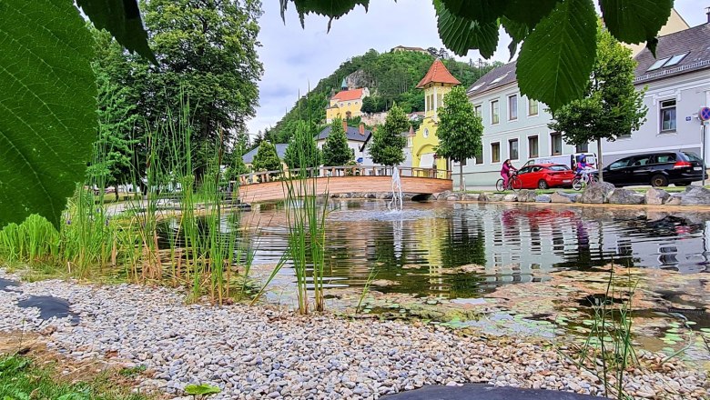 Ausblick von einen Park mit Teich und Brücke auf die Bergkirche Pitten