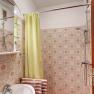 Kleines Badezimmer mit gelbem Duschvorhang, Waschbecken und gemusterten Fliesen.