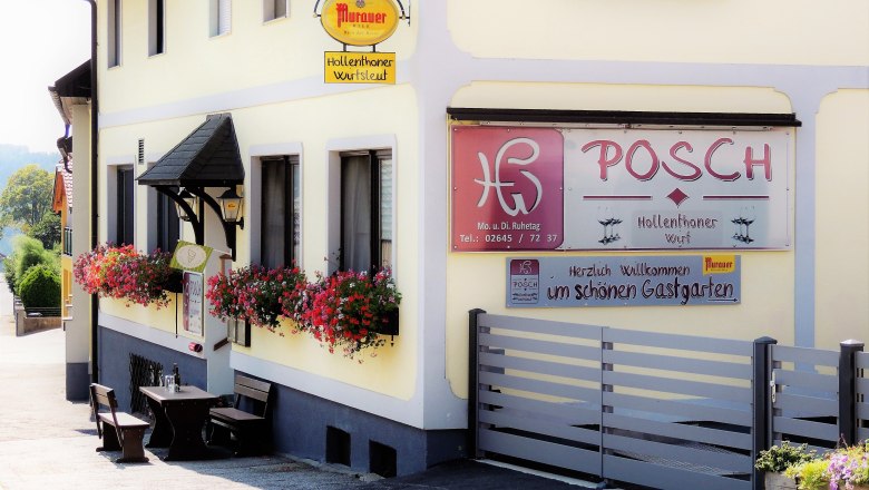 Au&szlig;enansicht des Gasthauses Posch mit Blumen und Sitzgelegenheiten.