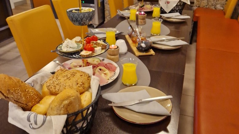 Fr&uuml;hst&uuml;ckstisch mit Br&ouml;tchen, Aufschnitt und Orangensaft in einem Caf&eacute;.