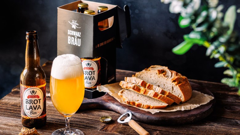 Eine Flasche Lava-Bier neben einem gefüllten Glas und geschnittenem Lava-Brot auf einem Holztisch.