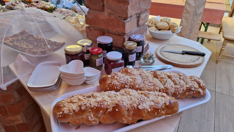 Ein Tisch mit Gebäck, Marmeladengläsern und Geschirr in Mei Kuchl.