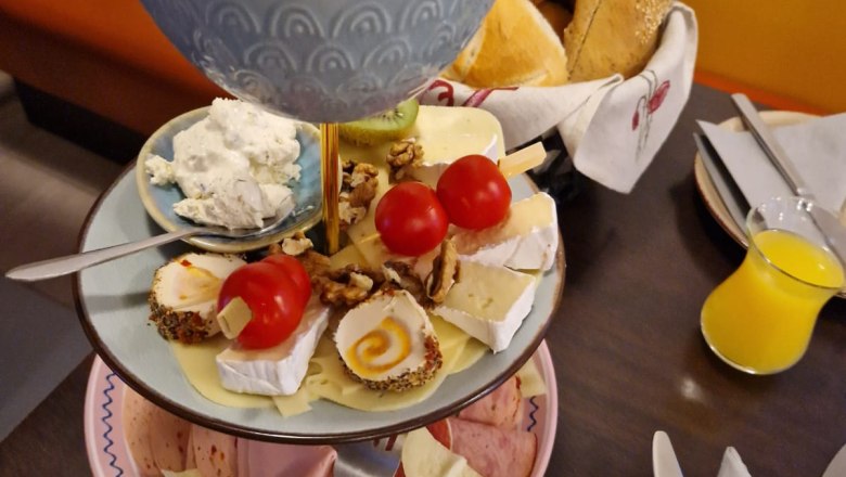 Fr&uuml;hst&uuml;cksetagere mit Aufschnitt, K&auml;se, Br&ouml;tchen und Butter im Caf&eacute;.