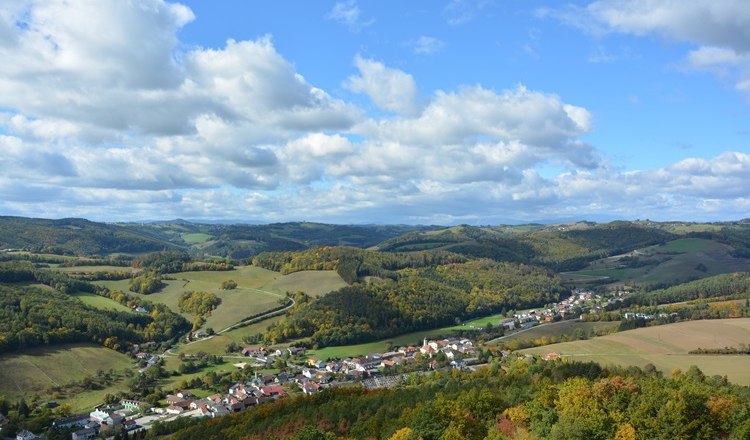 Landschaft mit H&uuml;geln, W&auml;ldern und einem Dorf im Herbst.